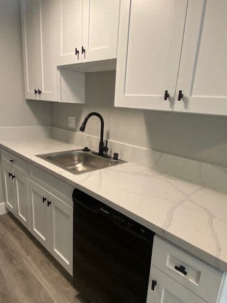 a kitchen with white cabinets and a black dishwasher